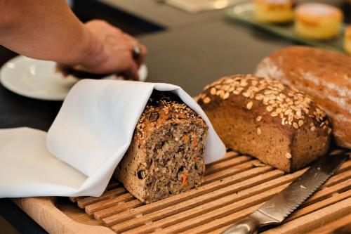 a person cutting a loaf of bread on a cutting board at Hotel Merkur - Superior in Baden-Baden