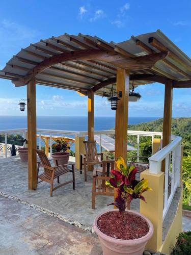 a wooden pergola with chairs and a table at The Victory Villa in Parrot Hall