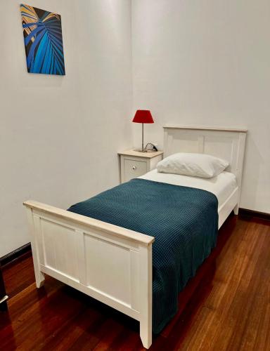 a bedroom with a white bed with a blue blanket at Villa Famiri Boutique hotel in Paramaribo
