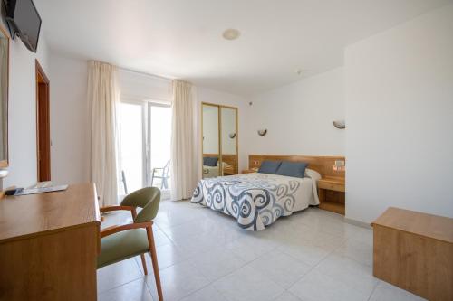 ein Hotelzimmer mit einem Bett, einem Schreibtisch und einem Tisch in der Unterkunft Hotel Paraimo in A Lanzada