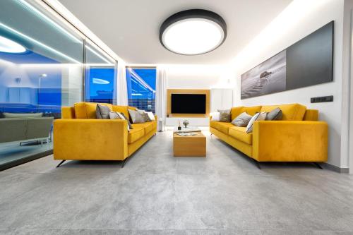 a living room with two yellow couches and a tv at Villa Sant Meloneras in Meloneras