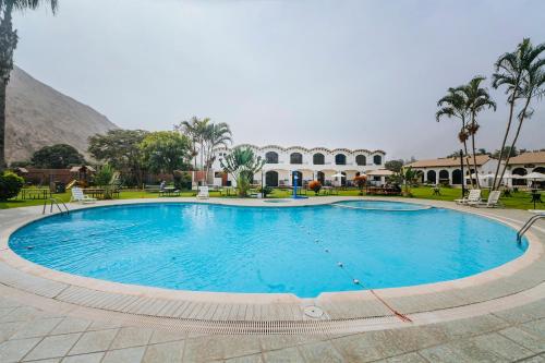 einem großen Pool mit Palmen und einem Gebäude in der Unterkunft VPX CLUB in Cieneguilla