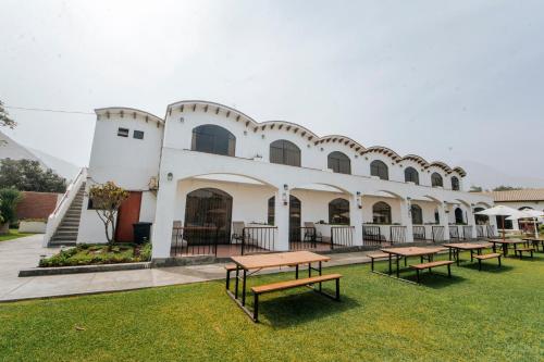 a building with picnic tables in the grass at VPX Hoteles Cieneguilla in Cieneguilla