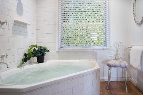 a bath tub in a white bathroom with a window at Aggies Way in Daylesford