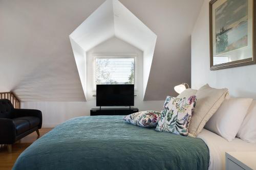 a bedroom with a bed with a chair and a television at Aggies Way in Daylesford