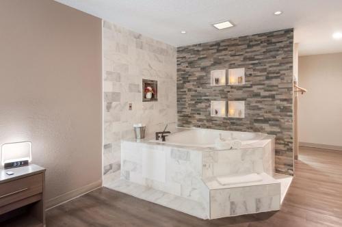 a bathroom with a tub and a stone wall at Red Roof Inn Dahlgren - Naval Base in Dahlgren