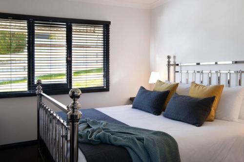 Un dormitorio con una cama con almohadas azules y amarillas. en Cricklewood- 2 bedroom enchanting miner's cottage, en Daylesford