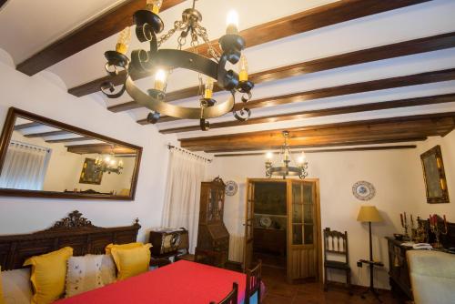 a living room with a chandelier and a red table at Casa Rural El Rincon del Infante in Villa de Don Fadrique