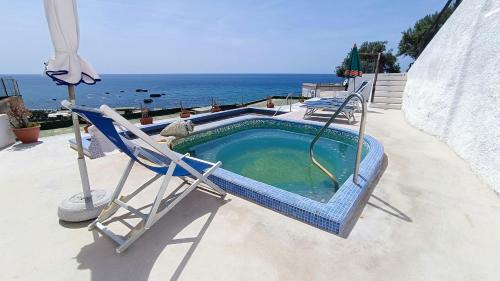 a chair and a swimming pool next to the ocean at La Dea del Mare in Ischia