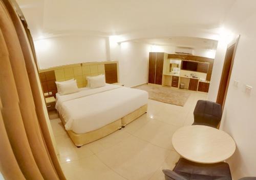 a bedroom with a white bed and a table and chairs at Diamond Star Hotel فندق النجمة الماسية in Seeb