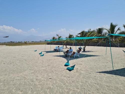 a group of people sitting on a beach with swings at SUITE CON TERRAZA PANORAMICA in Puebloviejo