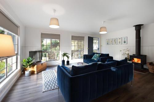 a living room with blue couches and a fireplace at Springview Cottage- captivating bush retreat in Hepburn Springs