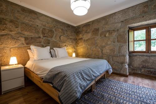 a stone walled bedroom with a bed and a window at Douro Senses - Nature House in Cinfães