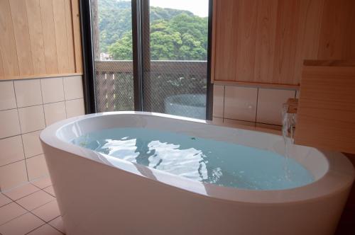 Kirishima miyama hotel في كيريشيما: حوض استحمام في الحمام مع نافذة