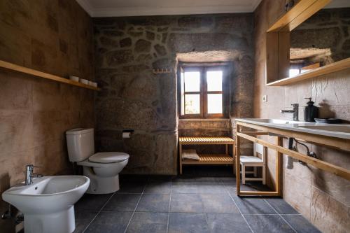 uma casa de banho com um lavatório, um WC e uma janela. em Douro Senses - Nature House em Cinfães