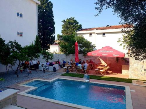 a pool in a courtyard with a group of people sitting at Black & White in Sutomore