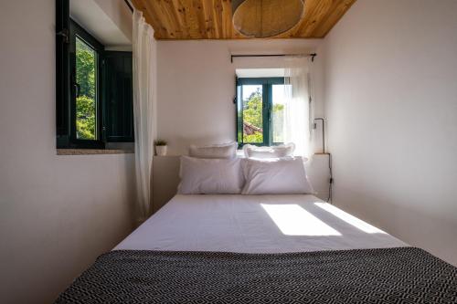 um quarto com uma cama com lençóis brancos e uma janela em Douro Senses - Village House em Cinfães