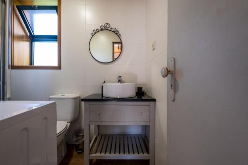 Baño blanco con lavabo y espejo en Douro Senses - Village House, en Cinfães