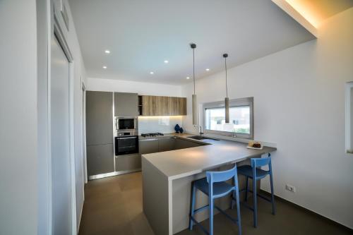 a kitchen with a counter and two blue bar stools at Casa Blanca Sea View in Marina di Ragusa