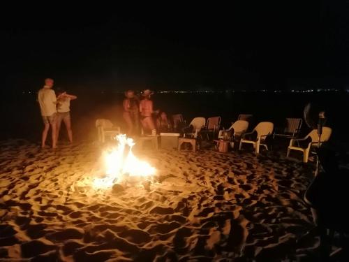 a group of people standing around a fire on a beach at SUITE CON TERRAZA PANORAMICA in Puebloviejo