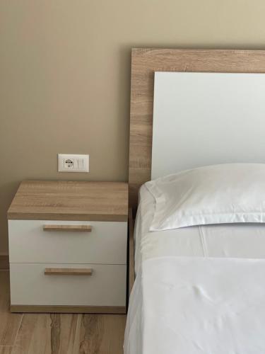 a bedroom with a bed and a nightstand with a alarm clock at Twentysix Apartment in Shkodër