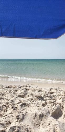 a beach with a blue umbrella and the ocean at Tiba soliman plage in Nabeul