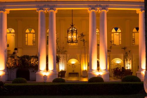 a large white building with columns at night at Hotel Solar do Império in Petrópolis