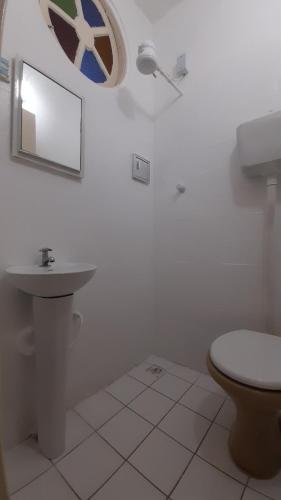 une salle de bain avec toilettes, lavabo et miroir dans l'établissement Suítes Recanto cama e café, à Arraial do Cabo