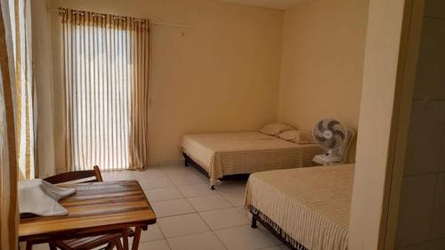 a room with two beds and a table and a window at Gold Star Village Kitnet equipado in Majorlândia