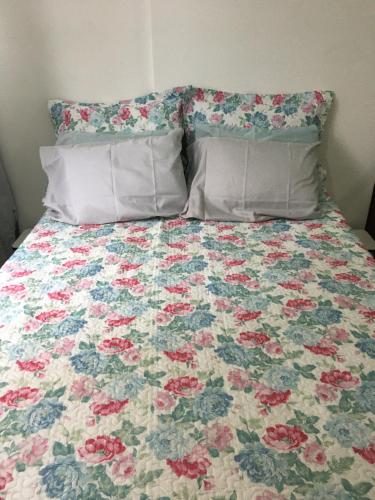 un letto con una trapunta floreale e 2 cuscini. di Meu Apartamento a 15min de Copacabana a Rio de Janeiro
