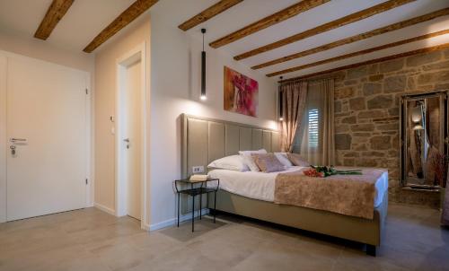 a bedroom with a bed and a brick wall at Old Spalatrum Luxury Rooms in Split