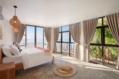 a bedroom with a white bed and large windows at Impossible Cliff House in Uluwatu