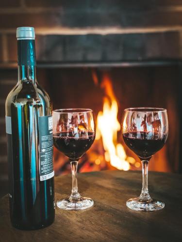 a bottle of wine and two glasses on a table with a fireplace at Pousada Toca da Onça in Gonçalves