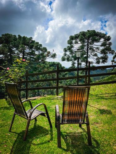 two chairs sitting in the grass next to a fence at Pousada Toca da Onça in Gonçalves
