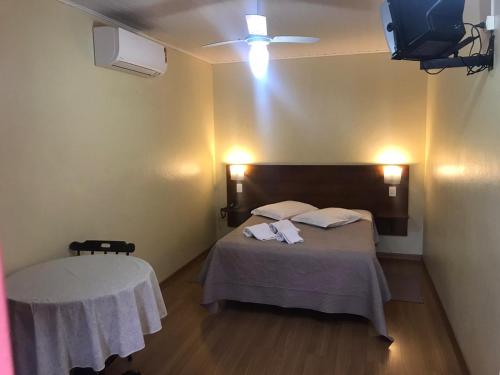 een slaapkamer met een bed met een tafel en een televisie bij Apartamentos Aromas de Gramado - Bairro Centro in Gramado