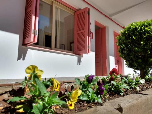 un jardín frente a una casa con ventanas rojas en Apartamentos Aromas de Gramado - Bairro Centro en Gramado