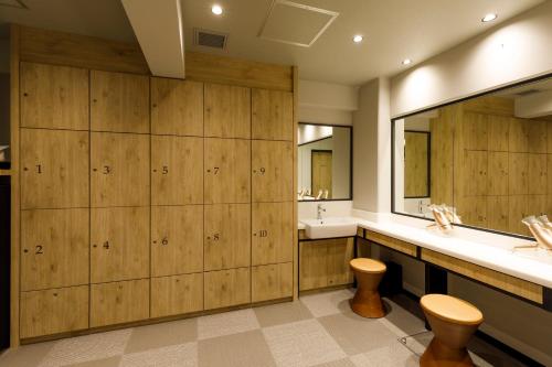 a bathroom with wooden cabinets and a sink and a mirror at Via Inn Shimonoseki in Shimonoseki