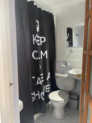 a bathroom with a toilet and a black shower curtain at Hermoso Depto Terraza in Rancagua