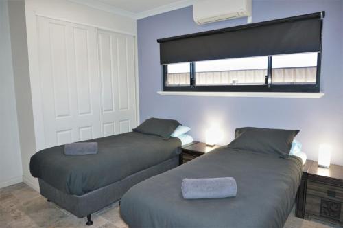 a bedroom with two beds and a window in it at 27 Corella Court in Exmouth