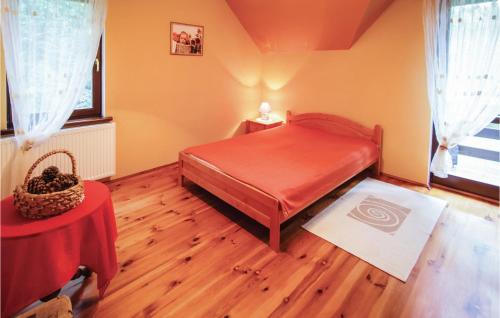 a bedroom with a red bed and a table at Lovely Home In Swietajno With Kitchen in Świętajno