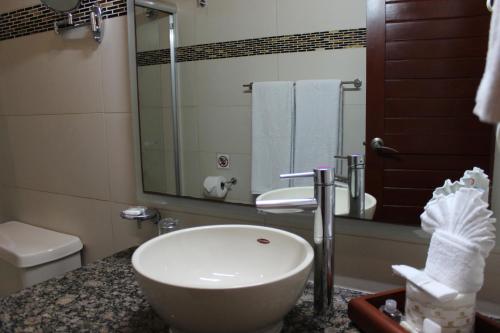 a bathroom with a sink and a toilet and a mirror at Grand City Hotel Cancun in Cancún