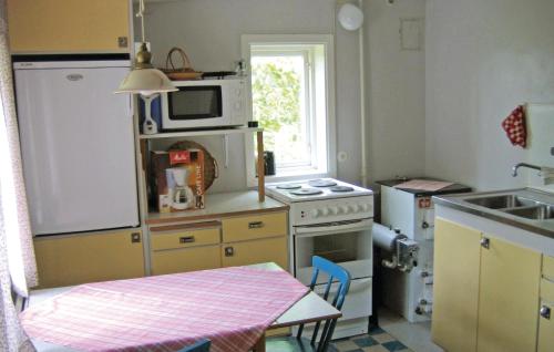 uma pequena cozinha com fogão e micro-ondas em 2 Bedroom Lovely Home In Frsund em Fårösund