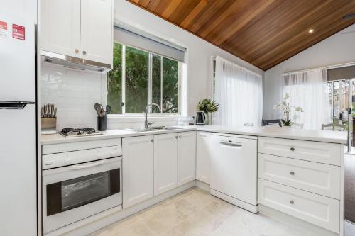 a kitchen with white cabinets and a wooden ceiling at Sails Five Inverloch in Inverloch