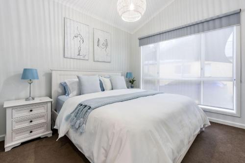 a white bedroom with a bed and a window at Sails Five Inverloch in Inverloch