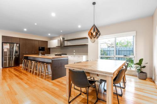 a kitchen with a wooden table and chairs at Inverloch Oasis L Oasi de Invy in Inverloch