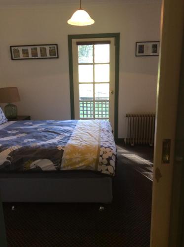 a bedroom with a bed and a window at Blue House at Mountainside Wines in Mount Cole
