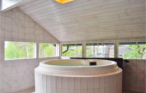 ein großes Bad mit einer großen Badewanne in einem Zimmer mit Fenstern in der Unterkunft Beautiful Home In Sndeled With Private Swimming Pool, Can Be Inside Or Outside in Søndeled