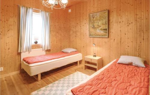 two beds in a bedroom with wooden walls and a window at Hjorten in Fegen