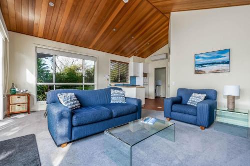 a living room with two blue couches and a table at Beachy Haven at Sails close to the Beach in Inverloch