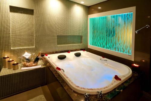 a bathroom with a bath tub with a large window at Sky Centro Hotel & SPA in Gramado